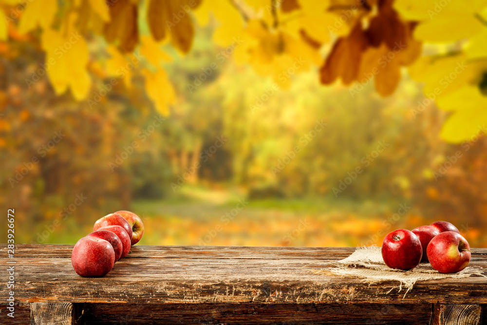 Red apples on wooden table top with autumn background. Empty space for decoration and products. - obrazy, fototapety, plakaty 