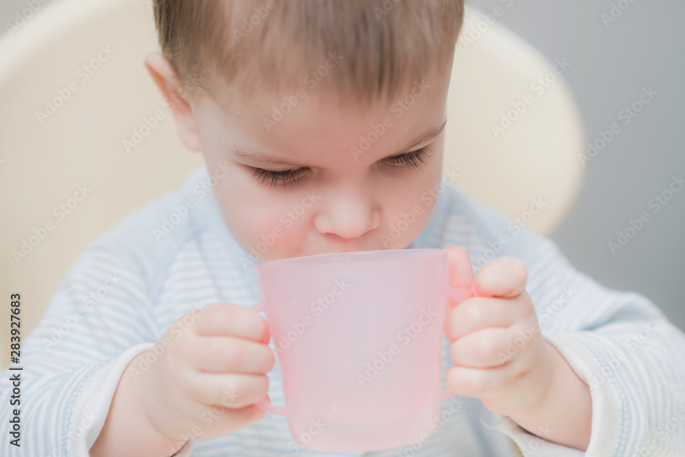 child in the kitchen drinking from a cup of water child in the kitchen drinking from a cup of water