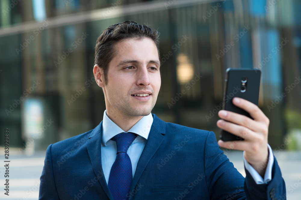 Happy young businessman is texting message on phone outdoor the glass bulding Happy young businessman is texting message on phone outdoor the glass bulding