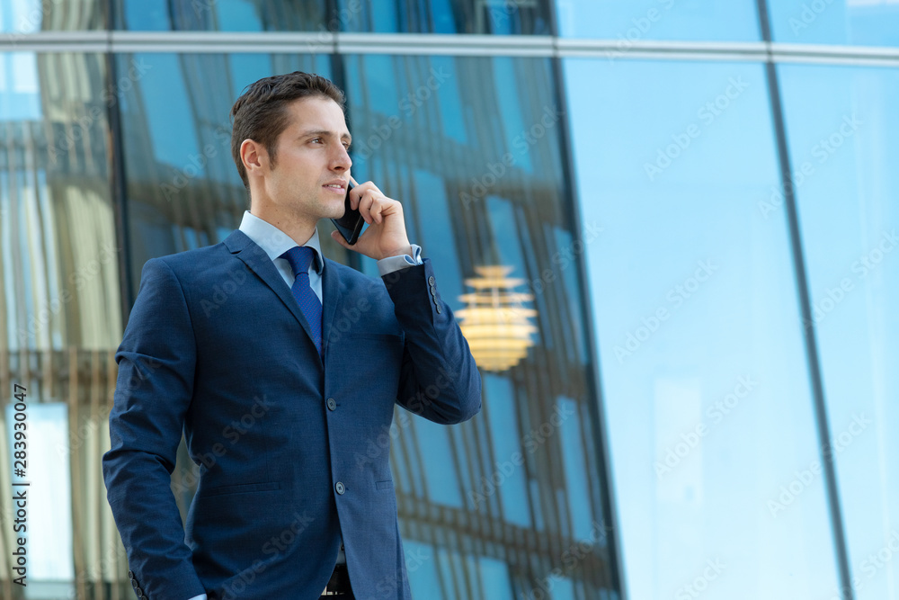 Happy young businessman is talking on phone outdoor the glass bulding Happy young businessman is talking on phone outdoor the glass bulding