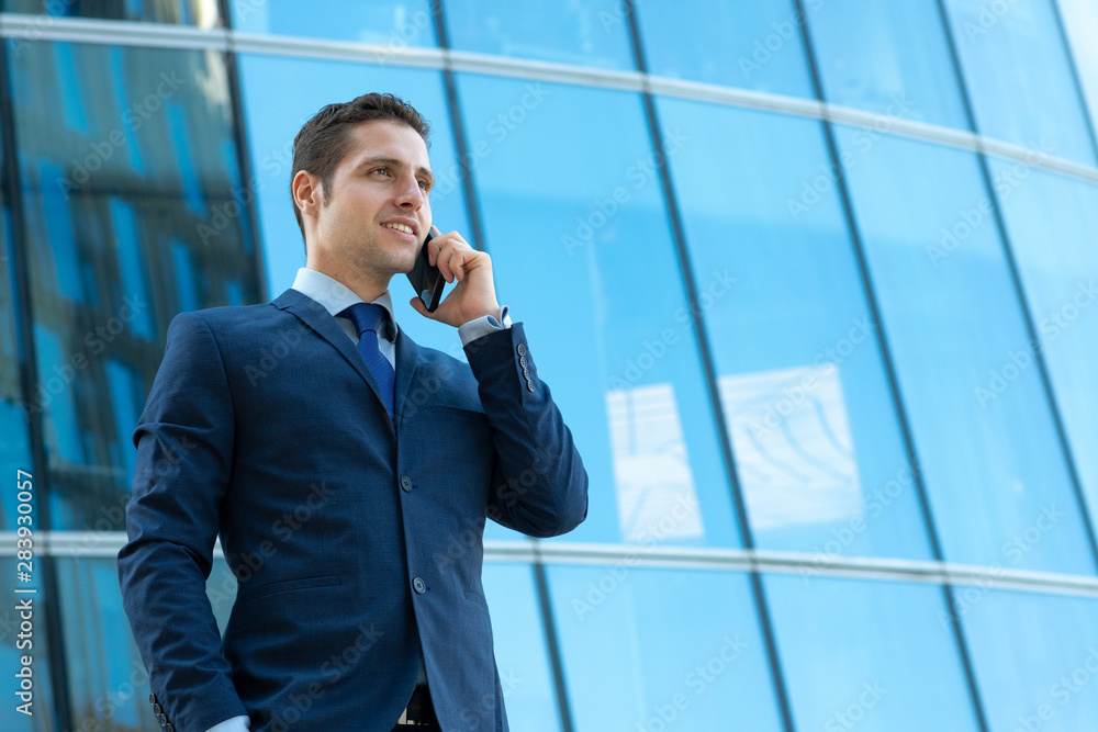 Happy young businessman is talking on phone outdoor the glass bulding Happy young businessman is talking on phone outdoor the glass bulding