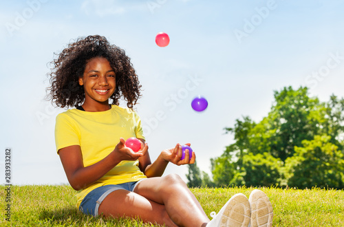 Girl juggle with balls on the lawn in park smiling photo