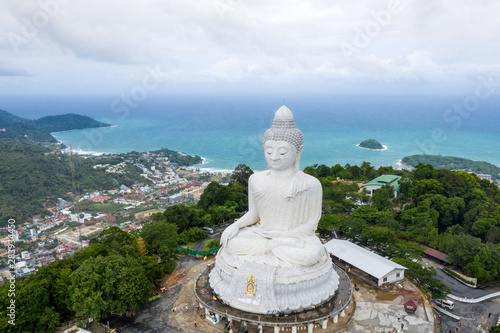 Aerial view of the white big buddha statue on top of mountain background with blue sky and ocean. The white Phuket big Buddha is the one of landmarks on Phuket island.