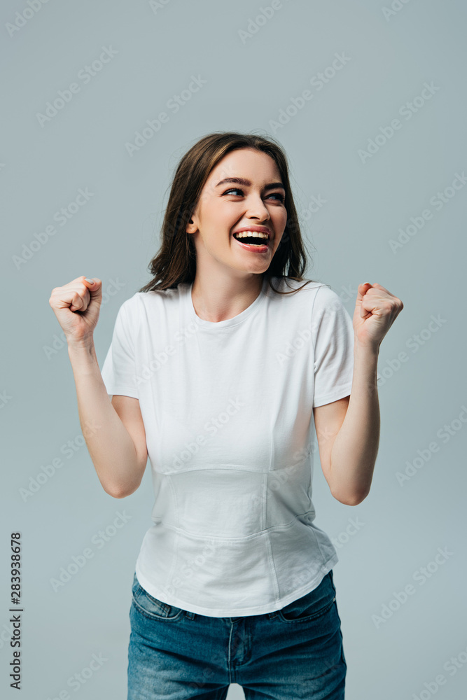 happy beautiful girl in white t-shirt showing yes gesture and looking away isolated on grey happy beautiful girl in white t-shirt showing yes gesture and looking away isolated on grey