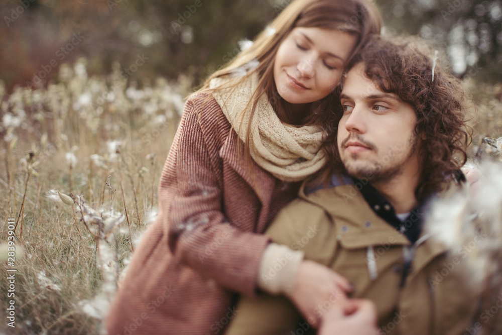 Obraz premium Young happy caucasian couple expecting a baby. Pregnant woman and her husband walking and having fun together outdoors in the autumn. Family, parenthood, love, happiness concept.