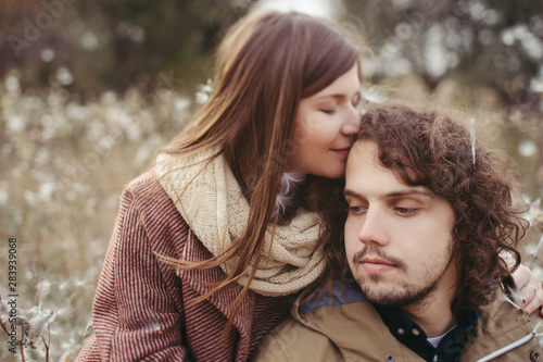 Young happy caucasian couple expecting a baby. Pregnant woman and her husband walking and having fun together outdoors in the autumn. Family, parenthood, love, happiness concept.