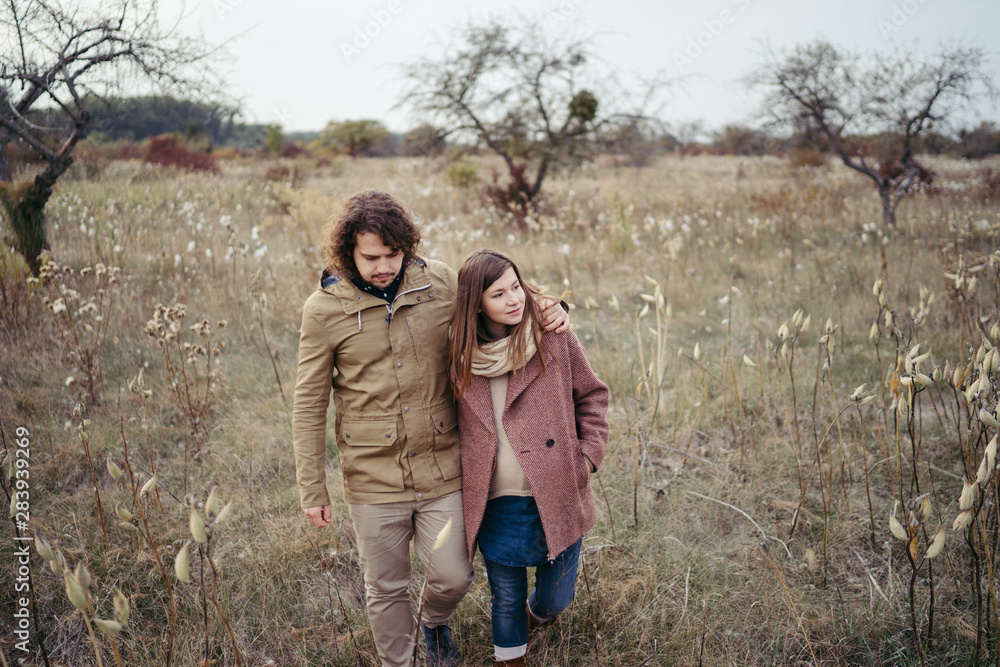 Young happy caucasian couple expecting a baby. Pregnant woman and her husband walking and having fun together outdoors in the autumn. Family, parenthood, love, happiness concept. Young happy caucasian couple expecting a baby. Pregnant woman and her husband walking and having fun together outdoors in the autumn. Family, parenthood, love, happiness concept.