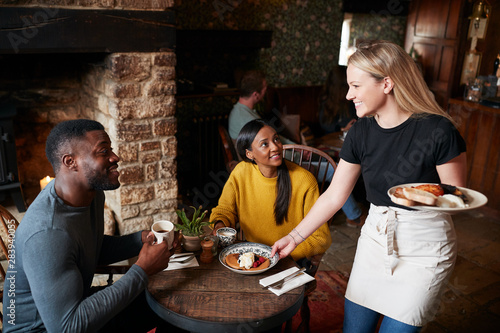 Waitress Working In Traditional English Pub Serving Breakfast To Guests photo
