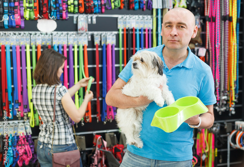 Ordinary man with dog looking bowl in pet store