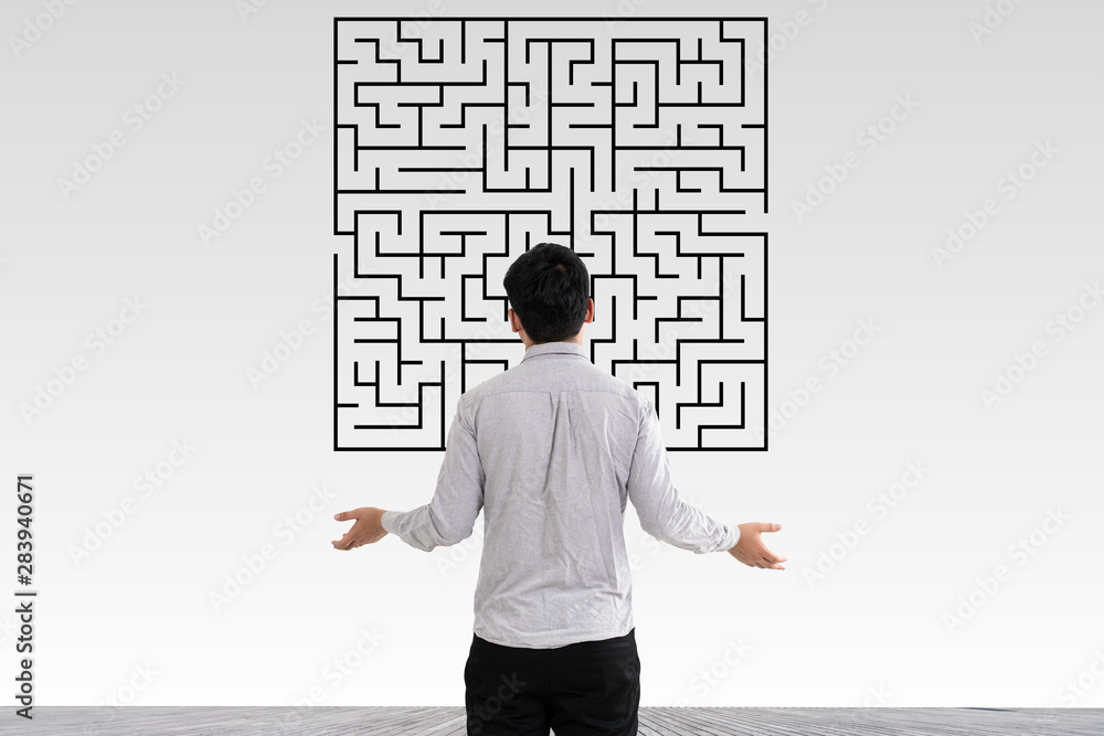 Businessman in doubt looking to a maze and searching the way out Businessman in doubt looking to a maze and searching the way out