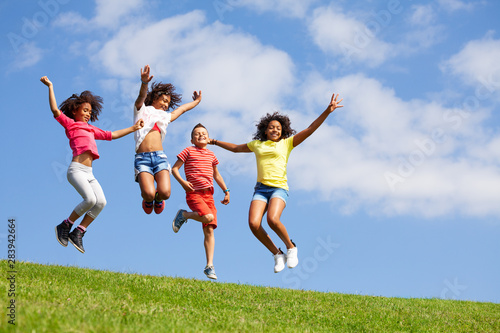 Group four jumping children over blue sky