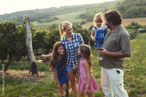 Happy wine grower family walking in vineyard