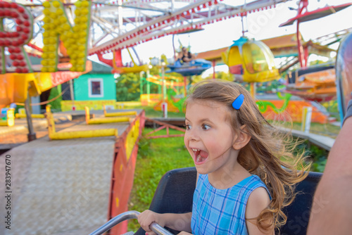 Fotografia Girl screaming and shouting happily while holding firmly on the colorful carouse