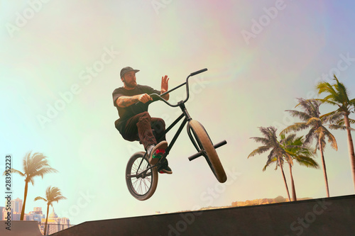 BMX rider is performing tricks in skatepark on sunset.