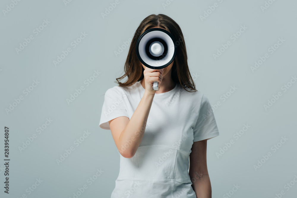 Fototapeta premium young pretty woman holding loudspeaker in front of face isolated on grey