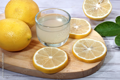  a cup of fresh lemon juice  and lemon slices  on cutting board