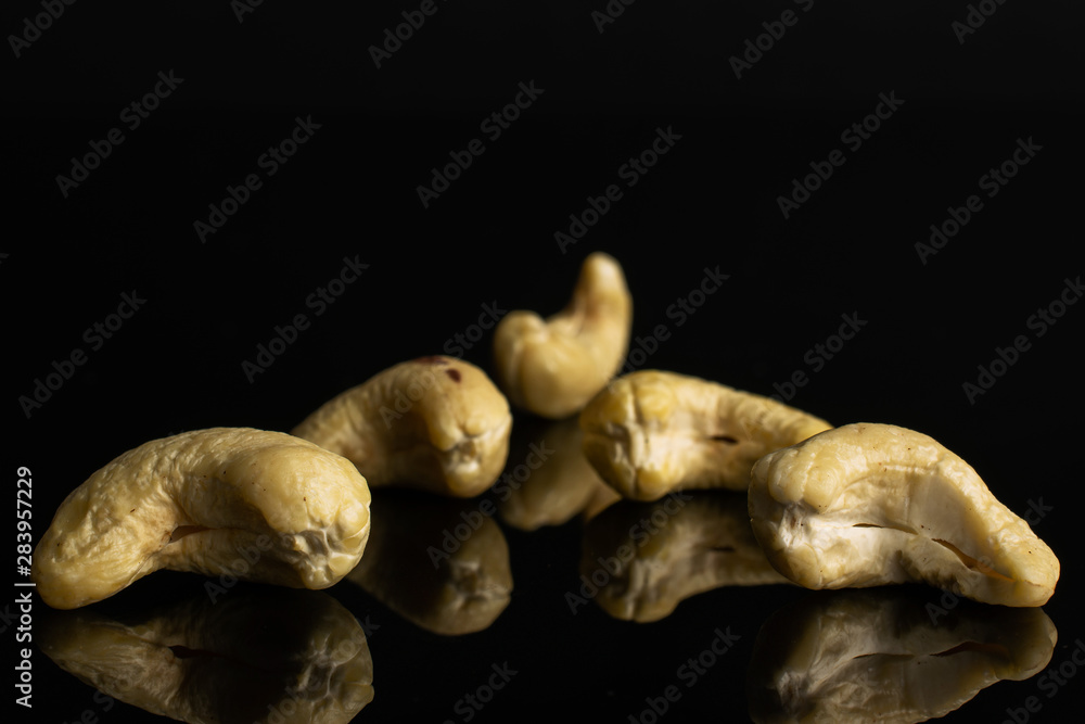 Group of five whole unsalted beige cashew isolated on black glass Group of five whole unsalted beige cashew isolated on black glass
