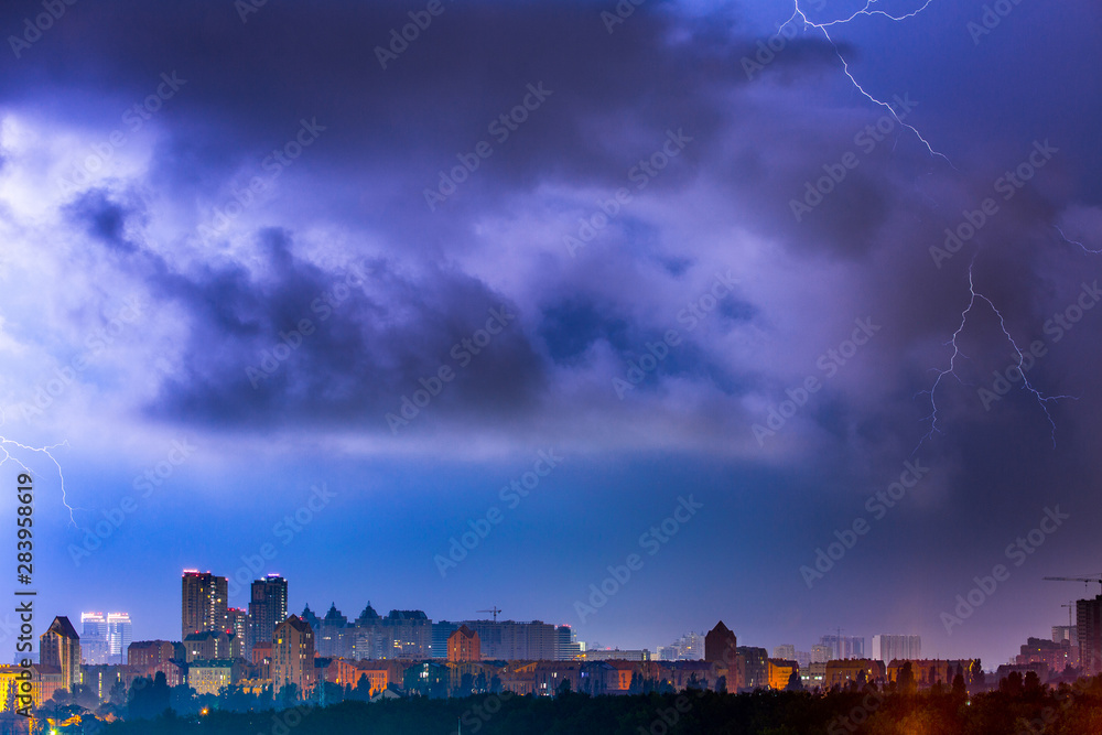 Lightning storm over the city at the summer heavy rain. Dramatic, breathtaking atmospheric natural phenomenon. Left bank outskirts of Kyiv, Ukraine.