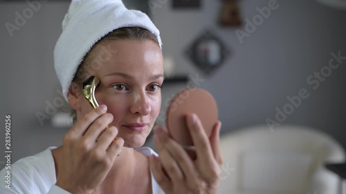 Beautiful woman is using derma roller. Woman is making needles procedure on face using mesoroller.