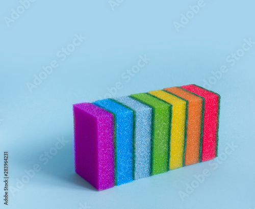 on a blue background are rectangular washcloths in a row of seven sponges for dishes to clean all rainbow colors