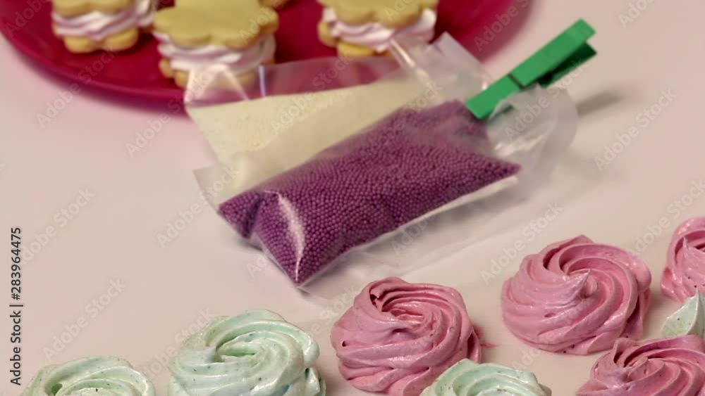 Making a marshmallow sandwich. Preparations of marshmallows and cookies lie on a plate. Near decorative multi-colored topping in bags. Making a marshmallow sandwich. Preparations of marshmallows and cookies lie on a plate. Near decorative multi-colored topping in bags.