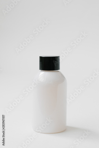 Plastic bottle with black cap for body care cosmetics or hair on white background. Side view