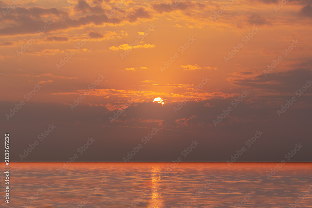 Fototapeta premium Bright sunset with yellow sun under the sea, Sky background on sunset. Nature composition.