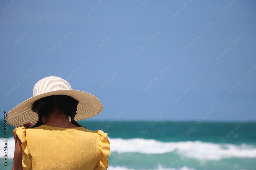 Behind of woman tourist on the beach with blue sea relaxing in summer