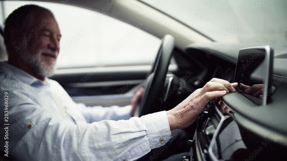 Senior man driver sitting in car, setting radio or navigation. Slow motion. Senior man driver sitting in car, setting radio or navigation. Slow motion.