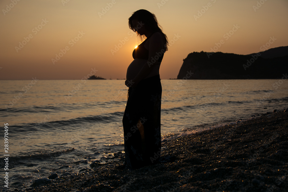 Silhouette of Pregnant woman at beach during sunset