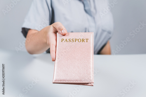 Immigration and passport control at the airport. woman border control officer with passport in the pink cover. Concept