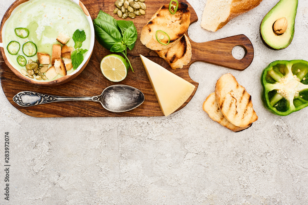 top view of green vegetable creamy soup on wooden chopping board on textured surface top view of green vegetable creamy soup on wooden chopping board on textured surface
