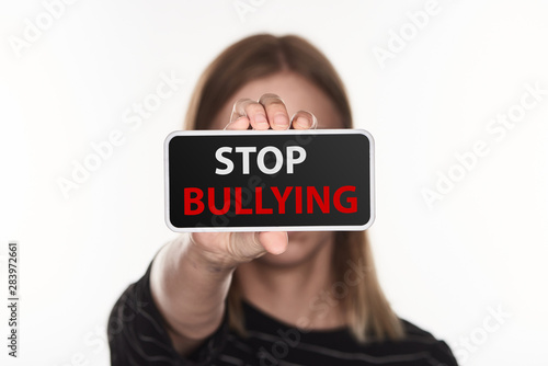 selective focus of victim of cyberbullying showing smartphone with stop bullying lettering on screen isolated on white