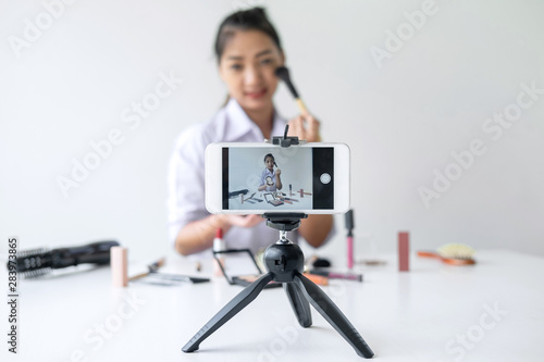 Business online on social media, Beautiful Asian woman blogger is showing present tutorial beauty cosmetic product and broadcast live streaming video to social network while recording teaching online