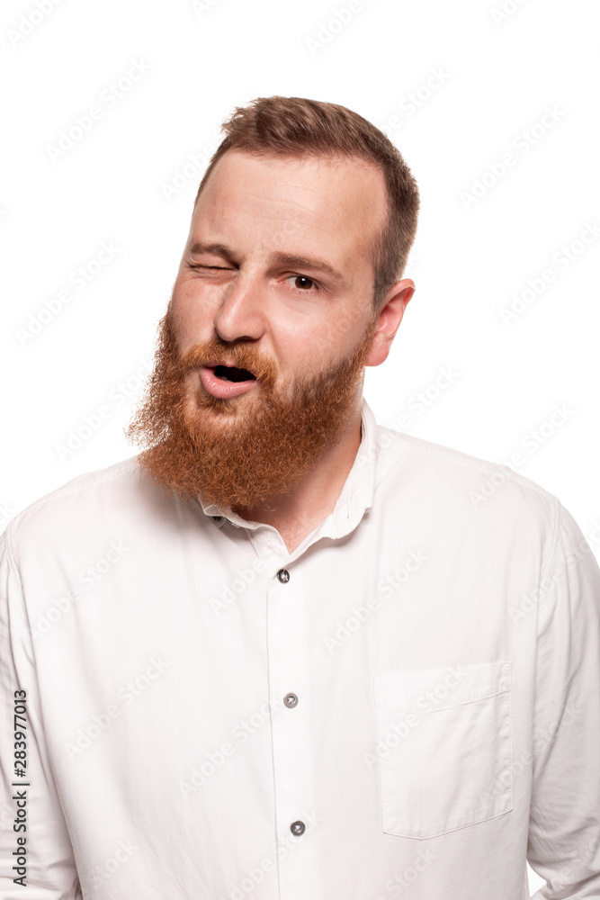 Portrait of a young, chubby, redheaded man in a white shirt making faces at the camera, isolated on a white background Portrait of a young, chubby, redheaded man in a white shirt making faces at the camera, isolated on a white background