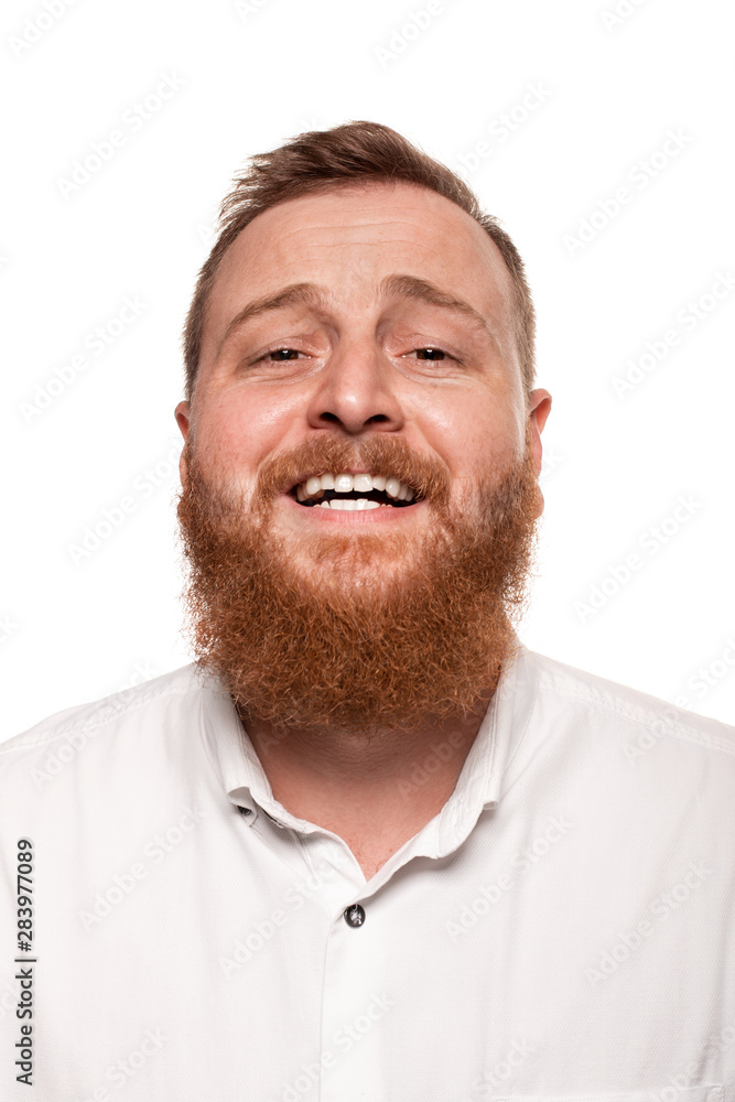 Portrait of a young, chubby, redheaded man in a white shirt making faces at the camera, isolated on a white background Portrait of a young, chubby, redheaded man in a white shirt making faces at the camera, isolated on a white background