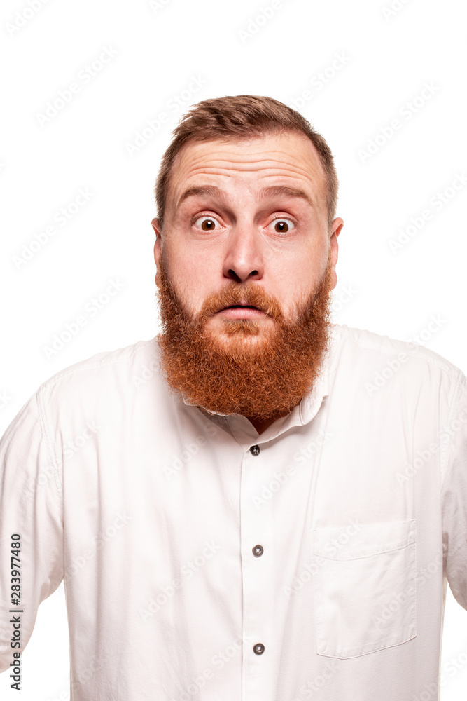 Portrait of a young, chubby, redheaded man in a white shirt making faces at the camera, isolated on a white background Portrait of a young, chubby, redheaded man in a white shirt making faces at the camera, isolated on a white background