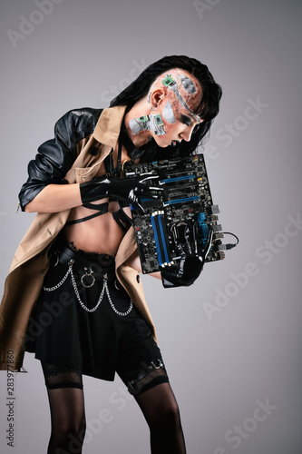 Young cyborg woman holding a motherboard 