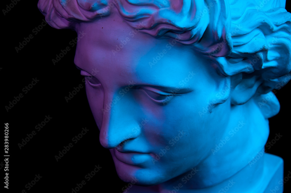 Gypsum copy of ancient statue Apollo head isolated on black background. Plaster sculpture man face.