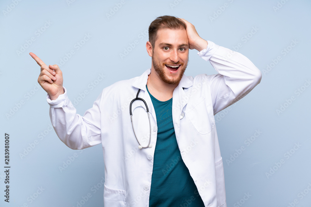 Handsome doctor man over blue wall surprised and pointing finger to the side Handsome doctor man over blue wall surprised and pointing finger to the side