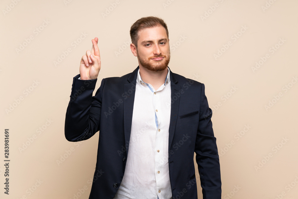 Blonde man over isolated background with fingers crossing and wishing the best Blonde man over isolated background with fingers crossing and wishing the best