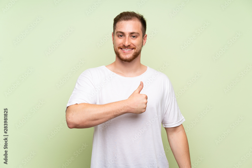 Handsome man over green background giving a thumbs up gesture Handsome man over green background giving a thumbs up gesture