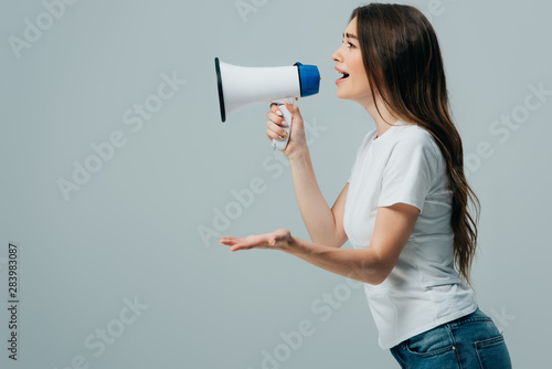side view of young pretty woman with loudspeaker isolated on grey