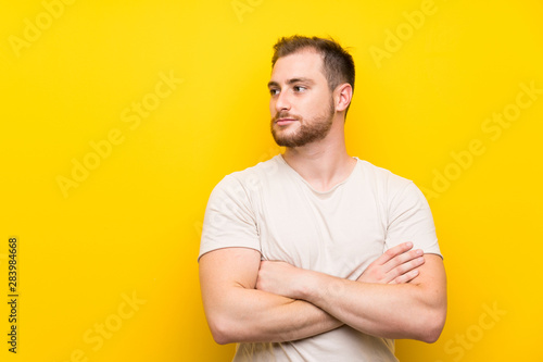 Handsome man over yellow background looking side