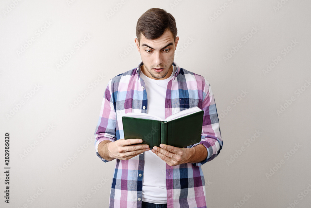 Young white man student studying lecture notes on gray background Young white man student studying lecture notes on gray background