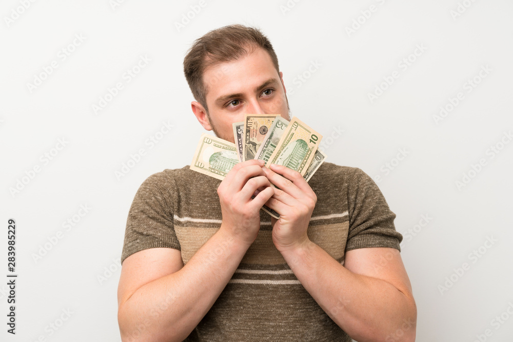 Handsome man over isolated white wall taking a lot of money Handsome man over isolated white wall taking a lot of money