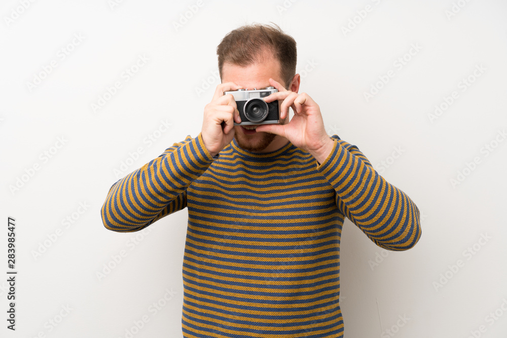 Handsome man over isolated white wall holding a camera Handsome man over isolated white wall holding a camera