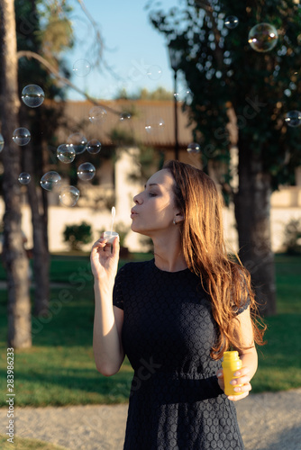 happy beautiful woman blowing soap bubbles outdoor