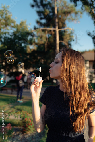 happy beautiful woman blowing soap bubbles outdoor