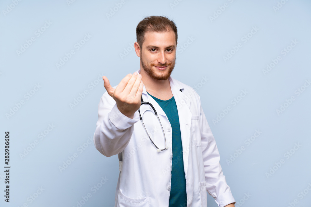 Handsome doctor man over blue wall inviting to come with hand. Happy that you came Handsome doctor man over blue wall inviting to come with hand. Happy that you came
